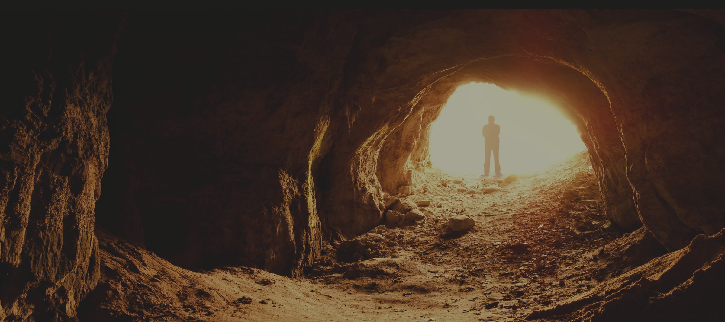 Figures walking through a lantern-lit cave toward the light
